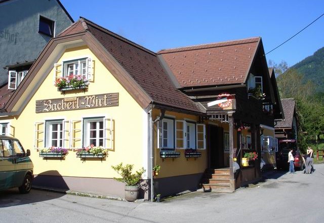Ein traditionelles Gasthaus mit gelber Fassade und Blumenk&auml;sten unter den Fenstern.