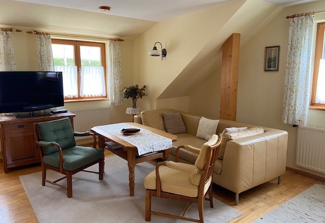 Gem&uuml;tliches Wohnzimmer mit Sofa, Sesseln und Fernseher.