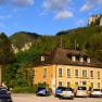 Ein gelbes Gebäude vor einer Bergkulisse mit geparkten Autos davor.