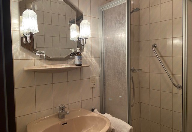 Ein Badezimmer mit Waschbecken, Spiegel, Dusche und Handtuch.