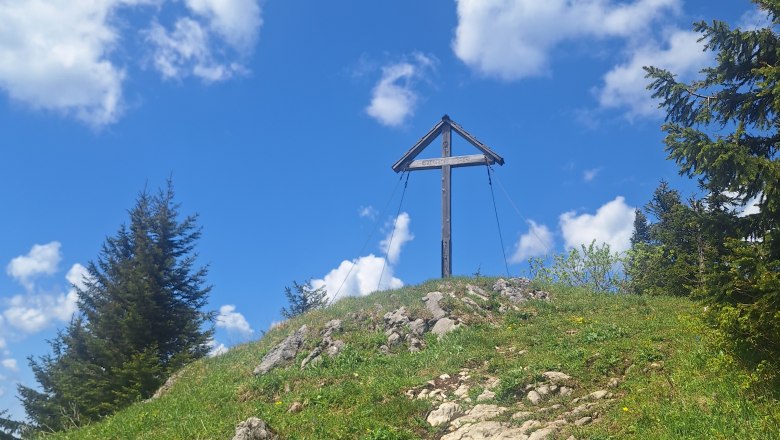 Gipfelkreuz aus Holz, davor ein Pfad der dorthin führt