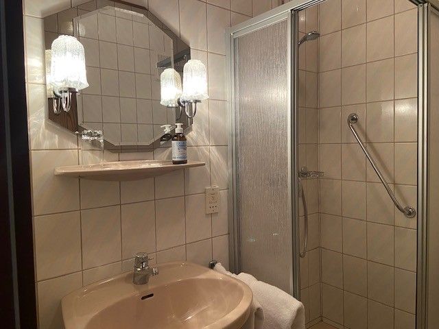 Ein Badezimmer mit Waschbecken, Spiegel, Dusche und Handtuch.