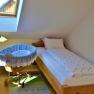 Ein gem&uuml;tliches Schlafzimmer mit Einzelbett, Babywiege und Dachfenster.