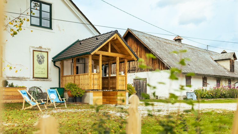Ein traditionelles Bauernhaus mit Holzbalkon und Liegest&uuml;hlen im Garten.
