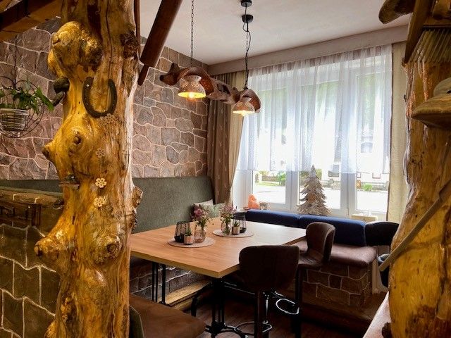Gemütliche Sitzecke mit Holztisch, umgeben von rustikalen Holzelementen und Steinwänden.